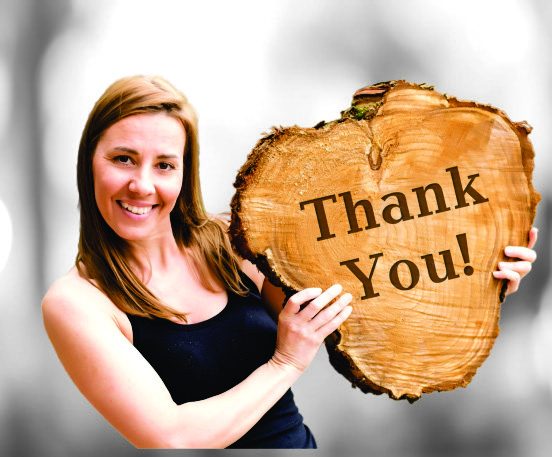 Kateryna, shop owner, holding a Thank You wood slice